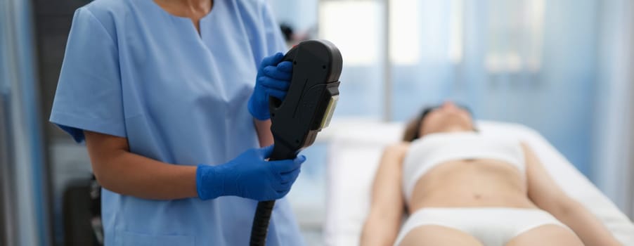 Beautician holding hybrid laser hair removal machine in beauty salon closeup. Aesthetic medicine laser hair removal concept