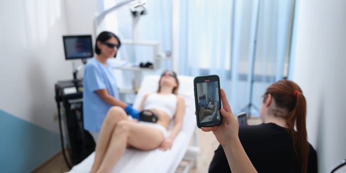 Smm manager filming laser hair removal video on mobile phone for social media ads closeup. Laser hair removal training concept