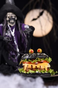 Monster Burger. Black bun, juicy beef cutlet, lettuce, onion, tomato and cheese in the shape of teeth, eyes with olives. Definitely a pick-me-up and a perfect Halloween party appetizer.