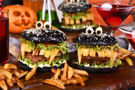Monster Burger. Black bun, juicy beef cutlet, lettuce, onion, tomato and cheese in the shape of teeth, mozzarella eyes with olives. Definitely a pick-me-up and a perfect Halloween party appetizer.