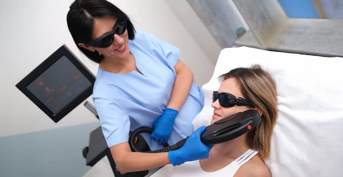 Beautician removing unwanted facial hair of client using laser in beauty salon. Aesthetic medicine laser hair removal concept