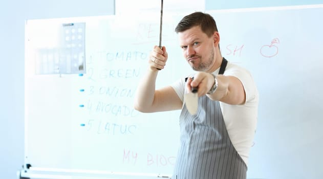 Portrait of standing man hold sharp kitchenware for cooking, knife sharpening on kitchen. Chef prepare for cooking dish. Cook, recipe, professional concept