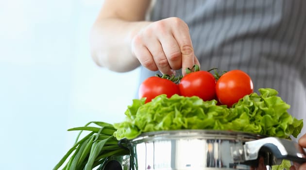 Close-up of chef put ripe tomatoes on lettuce, man cooking new recipe, try vegetarian food. Healthy culinary, hobby, yummy, veg eating, food, eco concept
