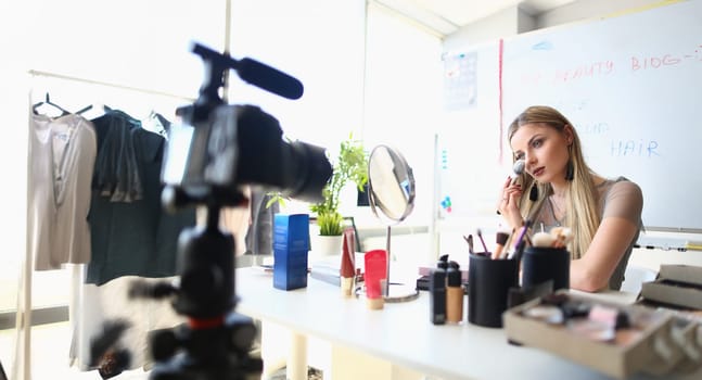 Portrait of beautiful woman present beauty products on videocamera, facial makeup tutorial. Blogger tell about makeup art. Beauty, mua, channel concept
