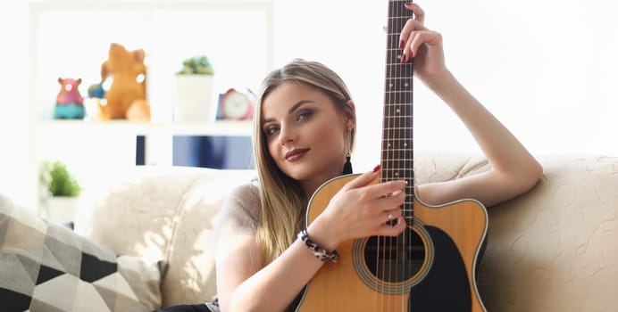 Portrait of young pretty woman playing on guitar, talented artist spend free time learning new song on musical instrument. Music, hobby, compose concept