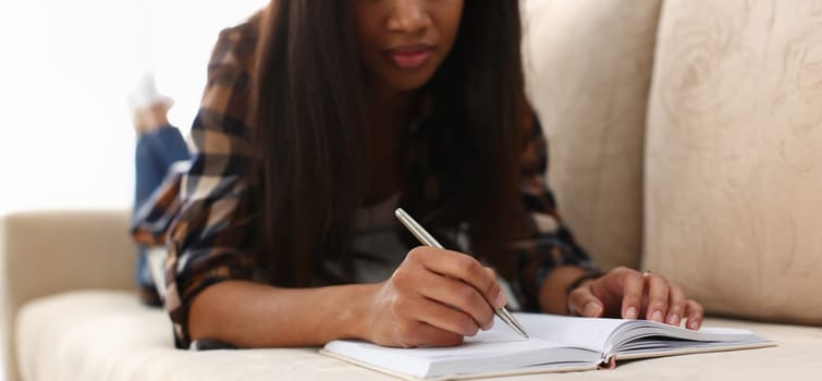 Close-up of afro american woman with open journal, writing in personal diary, chill on couch. Fresh start, planning, thought, idea, creative, mood concept