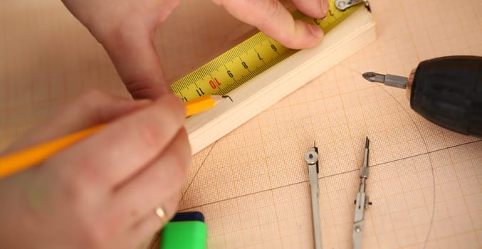 Close-up of foreman draw line on wooden piece, use measure tape and pencil. Talented worker on construction site. Renovation, building, architect concept