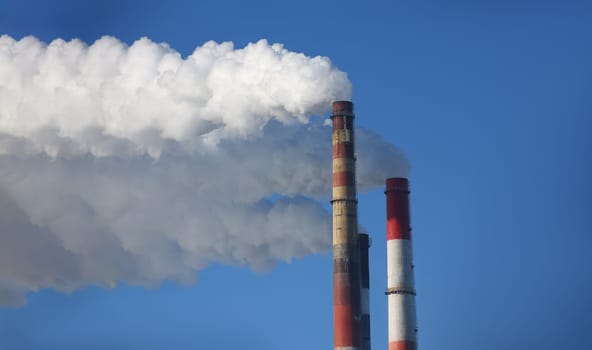 Close-up of power station with three smoke stacks, smoking pipes of heating supplying heat to city. Air pollution, ecology, smog problem, impact concept