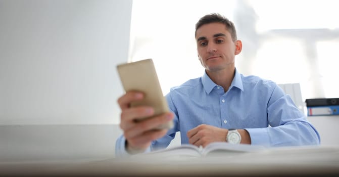 Portrait of concentrated worker using smartphone, chatting or surfing on internet. Kill time at work, bored, addiction, technology, digital world concept