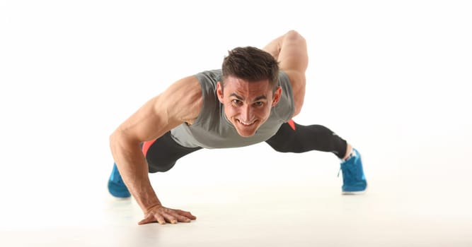Portrait of strong man perform biceps and triceps workout at home without equipment. Sport trainer train with smile, sweaty. Physical activity concept