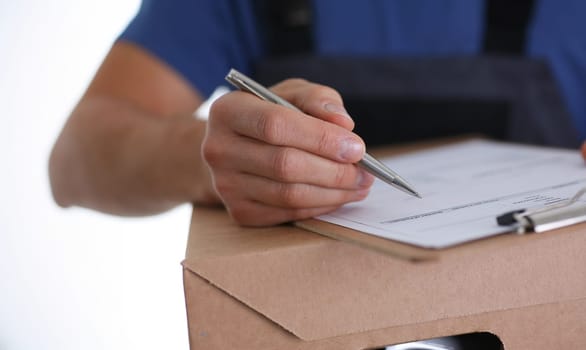 Close-up of man put signature on delivery receipt paper, got package from delivery service company. Delivery service, shipping, address delivery concept
