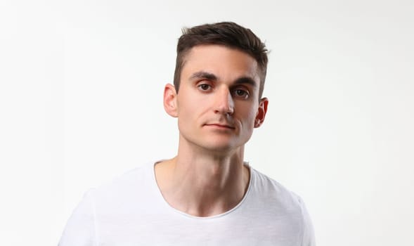 Portrait of young man with serious look, brunette man pose on white background. Handsome male model, attractive guy on photoshot. Modeling business concept