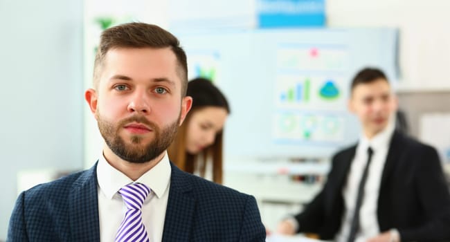 Portrait of successful businessman in presentable suit, colleagues on background, conference meeting. Success, human resources, business, career concept