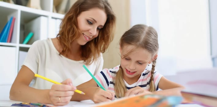 Portrait of mother and daughter painting with pencils in album, happy time with kid. Family spend time on weekend together. Development, hobby, art concept