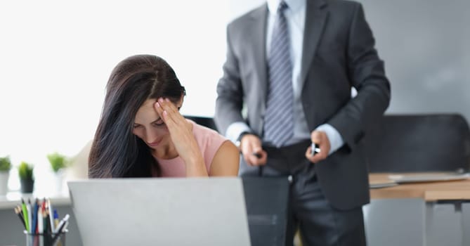 Portrait of secretary close face feeling ashamed and shy because of her boss harassment. Man stand behind with unzip belt on pants. Harassment at workplace