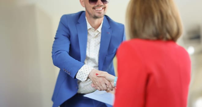 Portrait of handsome young man greeting woman with handshake dressed in trendy suit. Business meeting to sign up contract. Deal, agreement, success concept