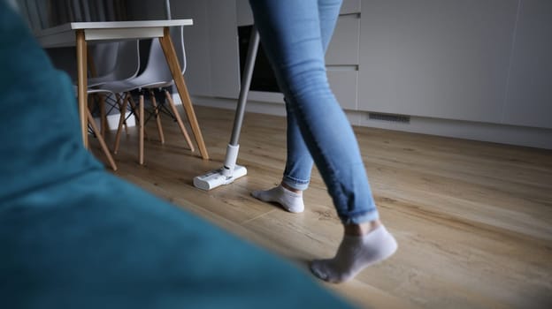 Close-up of female wiping wooden laminate with mop, domestic work, housewife cleaning at home. Cleaning routine, housekeeping, cleaning service concept