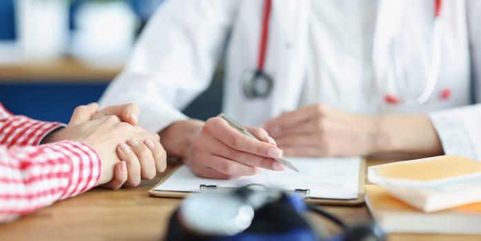Close-up of patient on appointment explain problem to medical worker in clinic. Doctor write complaints on paper. Healthcare, medicine, diagnostic concept