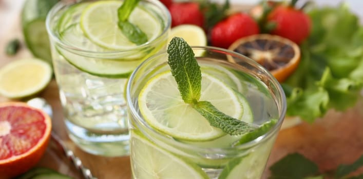 Close-up of cooling drinks cocktails in glasses on table, lime with lemon and mint, cheers or toast. Summer fruit beverages for company. Party, fun concept
