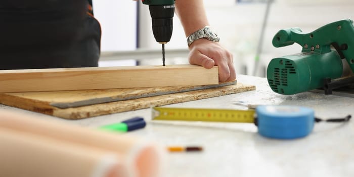 Close-up of workers instruments for repairing, man drill hole in wooden plank. Working mess on desk. Construction, builder, renovation, carpenter concept