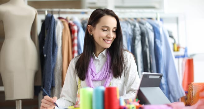 Smiling woman stylist designer at workplace in atelier. Seamstress profession concept