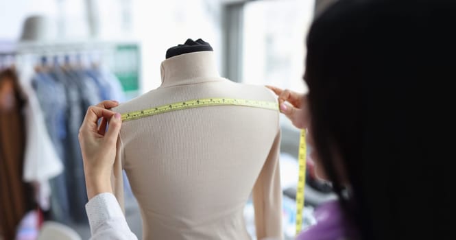 Female tailor takes measurements on mannequin. Atelier for repair and tailoring of stylish clothes concept