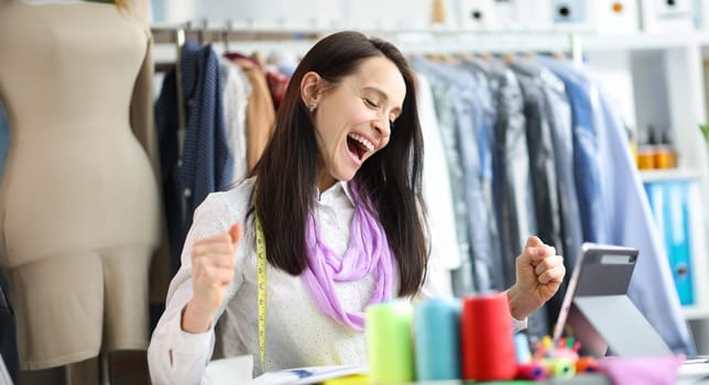 Joyful happy woman seamstress stylist at workplace. Successful fashion collection concept