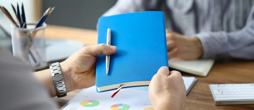 Businessman holding diary with pen at marketing meeting. Business analytics and statistics concept