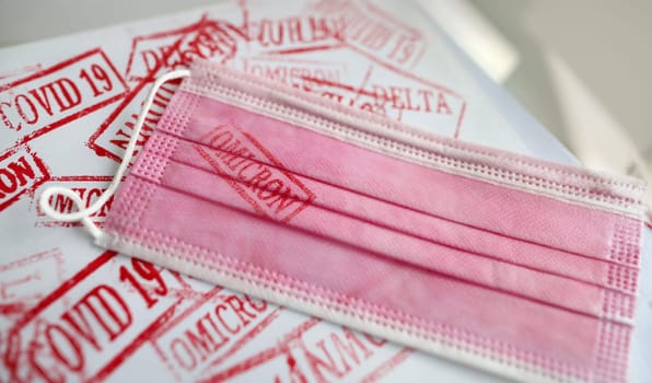 Pink medical mask with omicron print. Different new stamps coronavirus infection concept