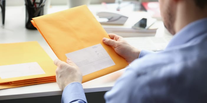 Close-up of man hold envelope, prepare package to give to courier for further delivery. Write address space on package. Delivery service, transfer concept