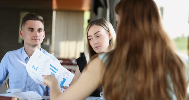 Portrait of business partners discuss report or contract on meeting in cafe outdoors, businesspeople listen to employee. Business, career, strategy concept