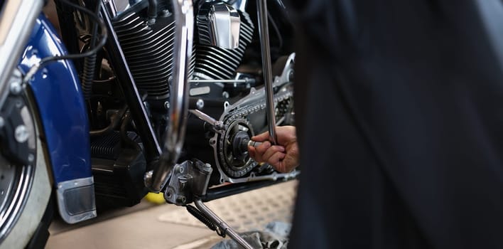 Close-up of professional mechanic fixing part of motorbike transport with wrench instrument. Pit stop for vehicle to get help. Maintenance service concept