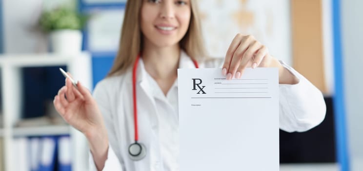 Portrait of smiling woman doctor hold prescription recipe in one hand and pen in another. Prescription paper for patient. Medicine, checkup, clinic concept