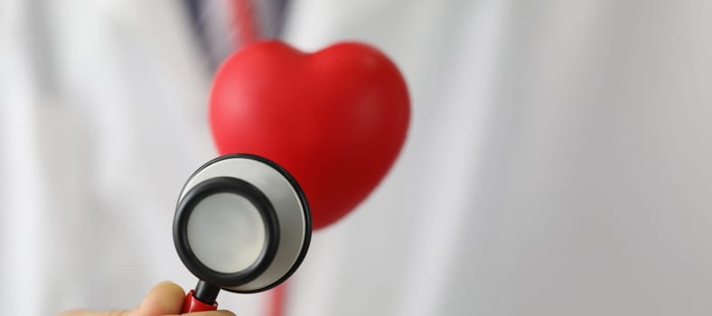 Close-up of medical stethoscope instrument listen to red plastic heart. Save life, full body checkup. Medicine, cardiology, healthcare, analysis concept