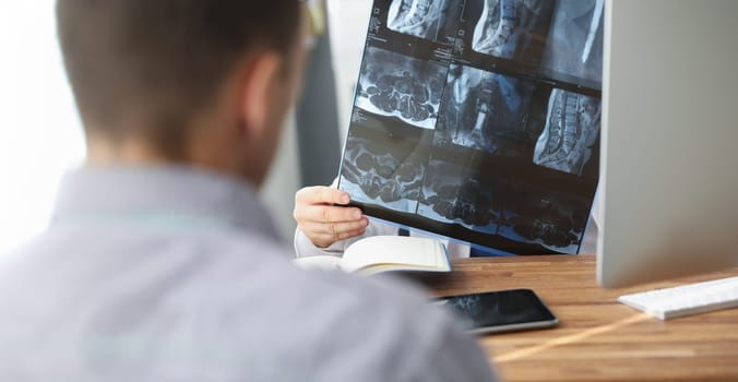 Close-up of doctor examining patients xray result in hospital on appointment with client. Scan of persons back. Healthcare, medicine, diagnostic concept