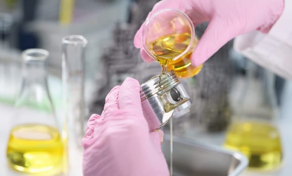 Close-up of mans hand in rubber gloves holding car part and pours lubricating oil on it. Mechanic fix component of vehicle. Lab, pit stop, handyman concept