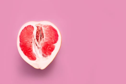 A half peeled grapefruit on a pink colored background. Minimal still life.