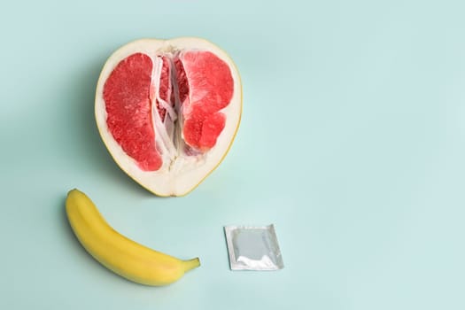 Safe sex. Juicy grapefruit and banana in a condom. The symbol of the vagina and penis from fruit.