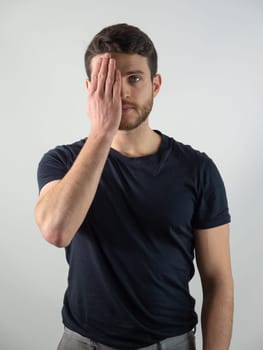 A man is seen with his face and one eye covered by his hand in a gesture of distress or sadness. His fingers appear tense, conveying a deep emotion through body language.