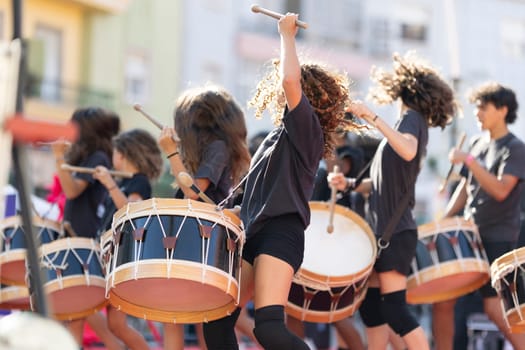 A group of people playing drums in a parade. Scene is energetic and lively