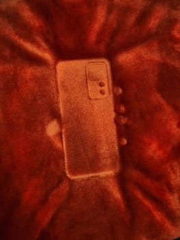 Phone mark on a fluffy blanket. Detailed print of a phone on a plush bedspread. Outline mark of a cellphone.