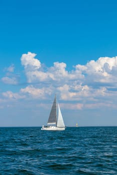 White sloop rigged yacht sailing in the Baltic sea at sunset. Clear sky after the storm, soft sunlight. Transportation, travel, cruise, sport, recreation, leisure activity, racing, regatta