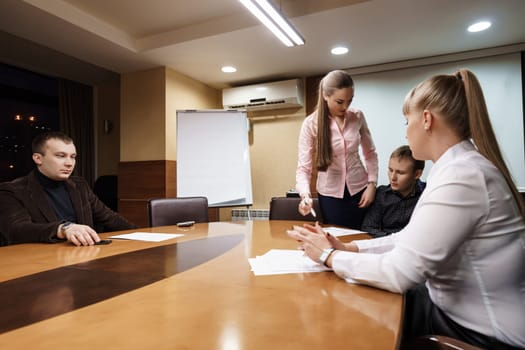Business meeting at company office. Several men and women in suits discussing working problems early in the morning