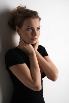 Young pretty blonde in black sexy tshirt with deep decollete posing in studio by the white wall