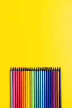 Set of multi-colored pencils on a yellow background.