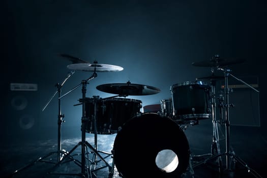 Modern drum set shot in smoky dark studio with sound equipment on the background