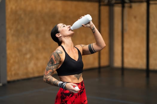 Horizontal photo with copy space of a tired athlete drinking water after working out in a gym