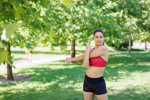 A sporty woman in activewear showcases the benefits of physical activity in a picturesque park, emphasizing fitness, wellbeing, and outdoor pastimes as key components of a healthy lifestyle