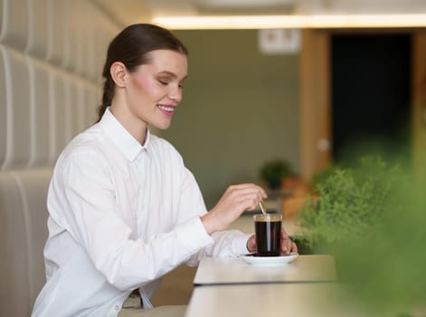 Side view photo of a smiling beauty elegant woman drinking coffee in a modern cafeteria