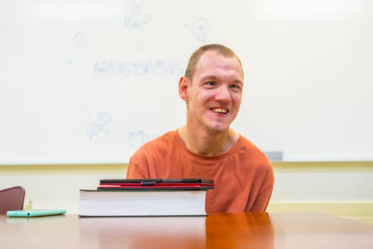Man with cerebral palsy in the university studying with digital tablet